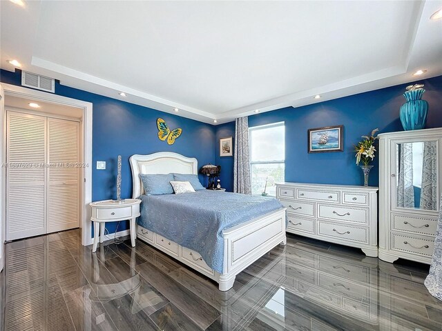 bedroom with dark hardwood / wood-style floors and a raised ceiling