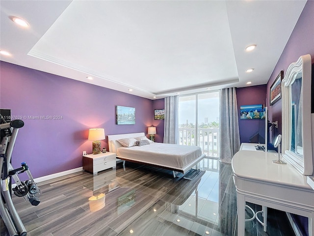 bedroom featuring a raised ceiling, access to exterior, and dark wood-type flooring