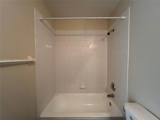 bathroom with toilet and tiled shower / bath