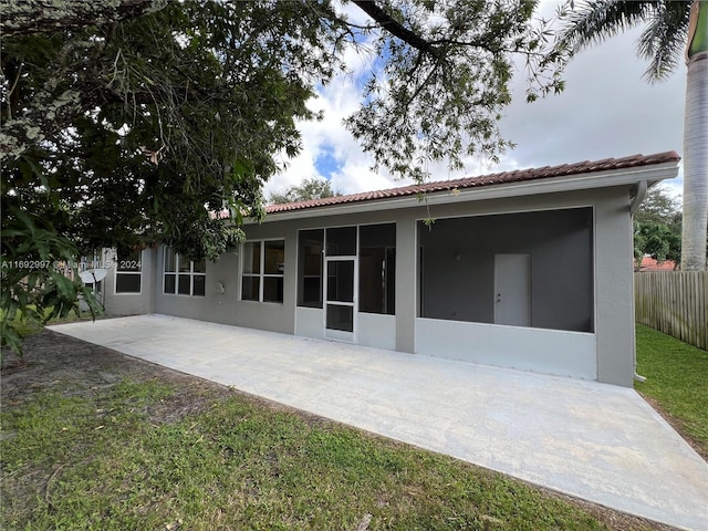 back of house featuring a lawn, a sunroom, and a patio