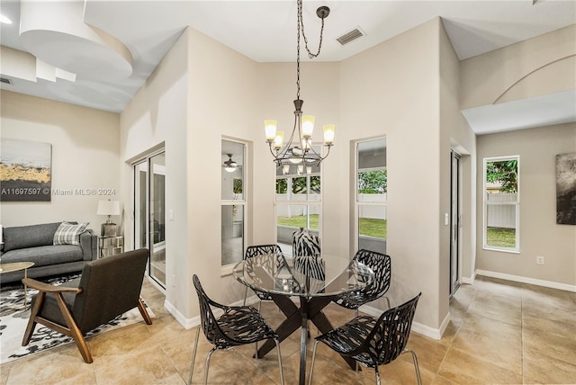 dining room featuring ceiling fan with notable chandelier, a towering ceiling, and a healthy amount of sunlight