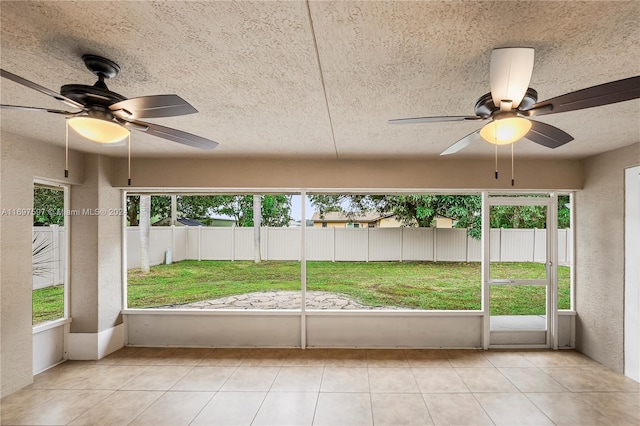 unfurnished sunroom featuring ceiling fan and a healthy amount of sunlight