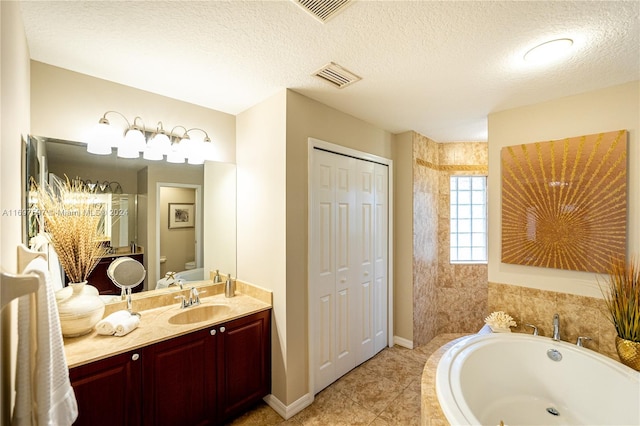 bathroom with vanity, tile patterned floors, toilet, a textured ceiling, and tiled bath