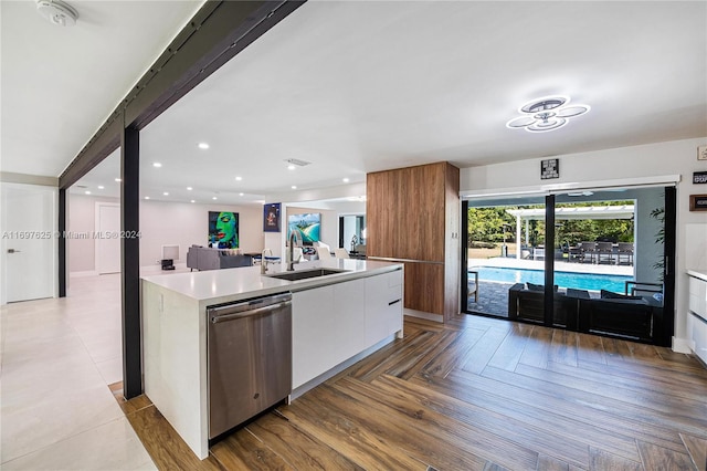 kitchen with white cabinetry, sink, parquet floors, stainless steel dishwasher, and a kitchen island