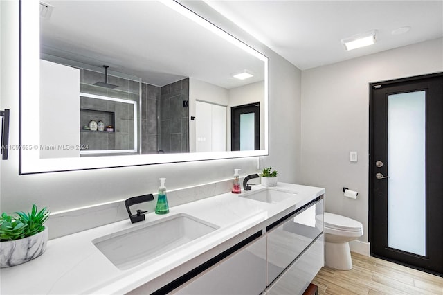 bathroom with vanity, toilet, wood-type flooring, and a tile shower