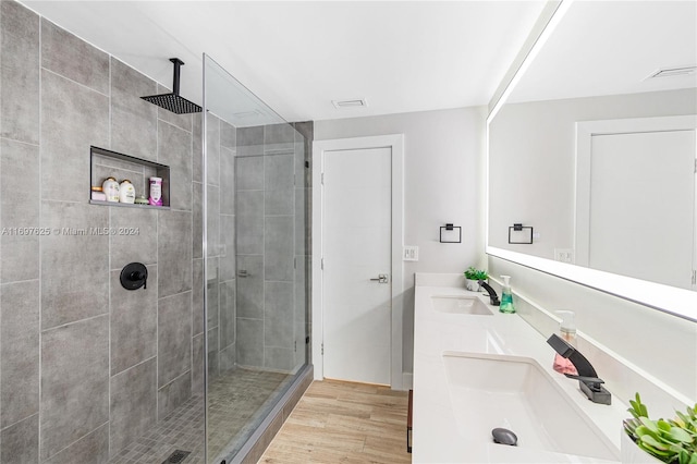 bathroom with hardwood / wood-style flooring, vanity, and a tile shower