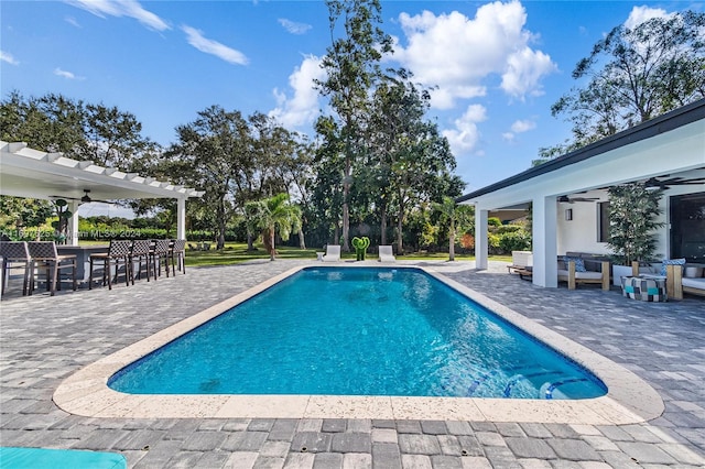 view of swimming pool featuring exterior bar, outdoor lounge area, a patio, and ceiling fan