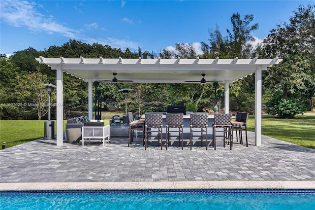 view of pool with a pergola, exterior bar, ceiling fan, a patio, and a lawn