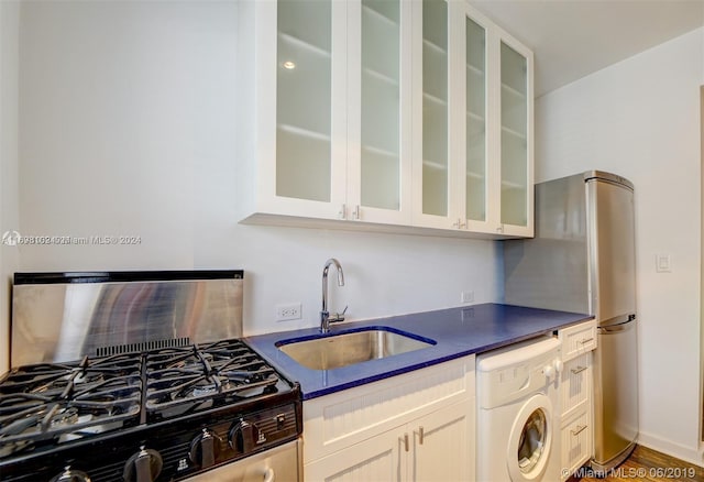 kitchen with dark hardwood / wood-style floors, sink, washer / clothes dryer, and stainless steel appliances