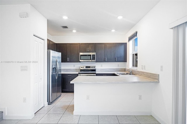 kitchen featuring sink, light tile patterned floors, dark brown cabinets, kitchen peninsula, and stainless steel appliances