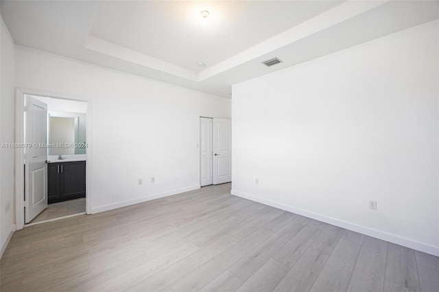 interior space featuring a raised ceiling, light wood-type flooring, and sink