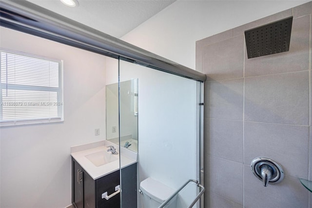 bathroom with tiled shower, vanity, and toilet