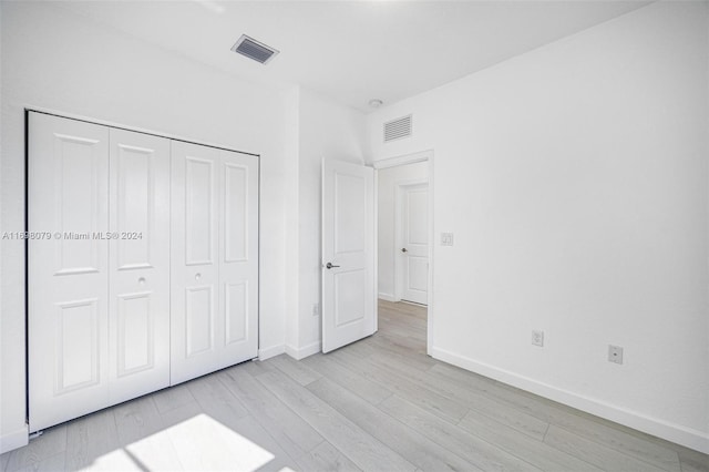 unfurnished bedroom with light hardwood / wood-style flooring and a closet