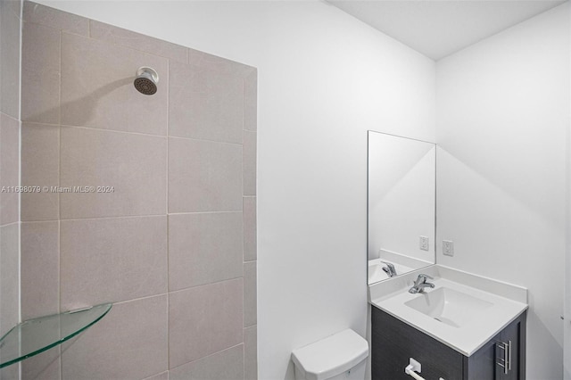 bathroom with vanity, toilet, and tiled shower