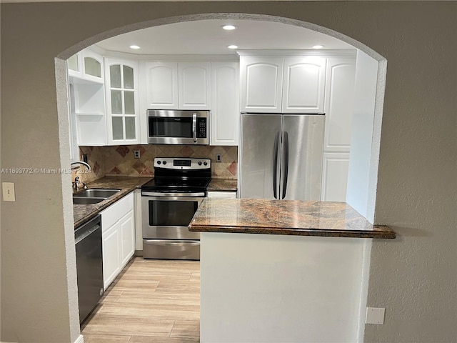 kitchen featuring light wood-type flooring, tasteful backsplash, stainless steel appliances, sink, and white cabinets