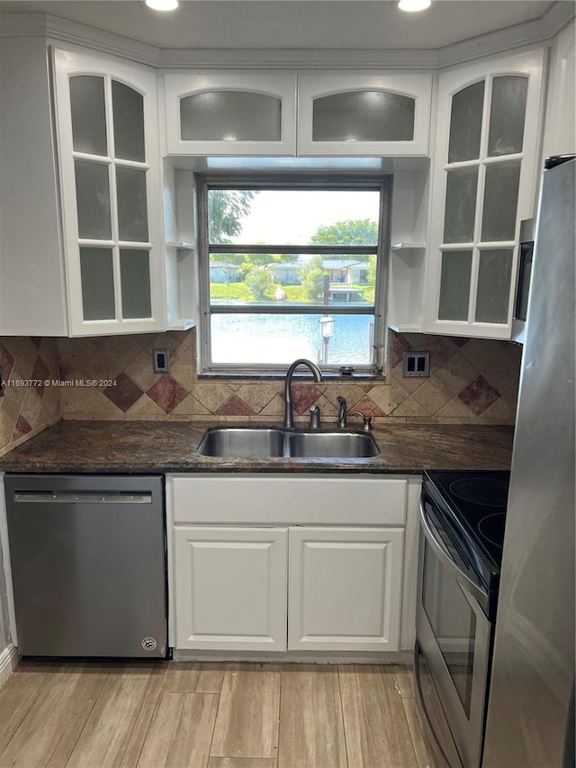 kitchen with white cabinets, sink, appliances with stainless steel finishes, tasteful backsplash, and light hardwood / wood-style floors