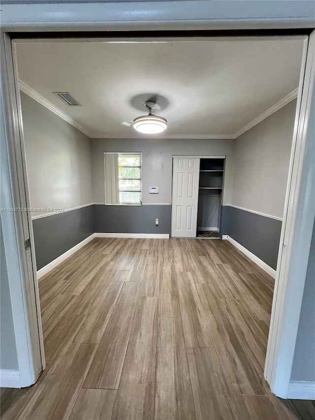 unfurnished bedroom with crown molding and wood-type flooring