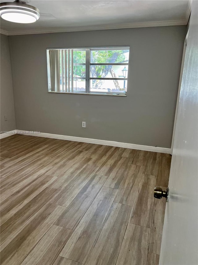 empty room with light hardwood / wood-style floors and ornamental molding