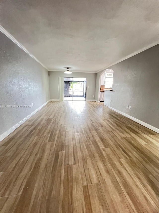 unfurnished living room featuring wood-type flooring and ornamental molding