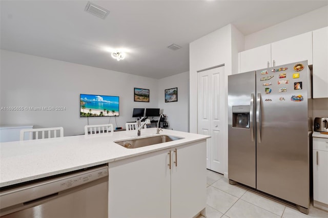 kitchen with white cabinets, sink, light tile patterned floors, light stone counters, and stainless steel appliances