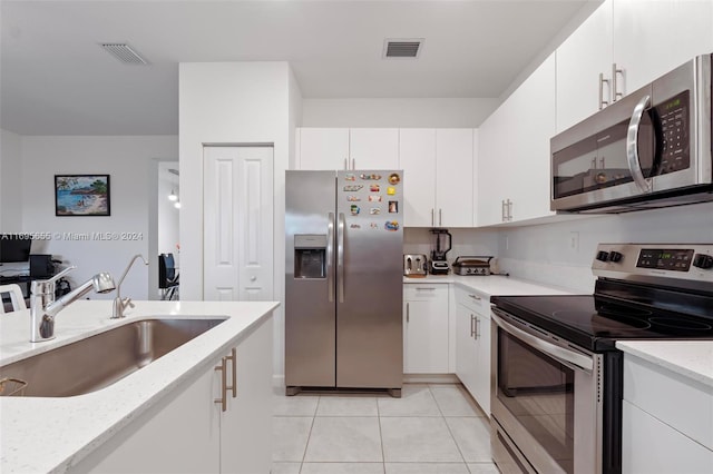 kitchen with white cabinets, sink, light tile patterned floors, and appliances with stainless steel finishes