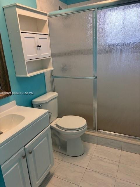 bathroom featuring tile patterned floors, toilet, vanity, and walk in shower