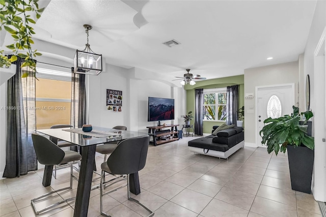 tiled dining space with ceiling fan with notable chandelier