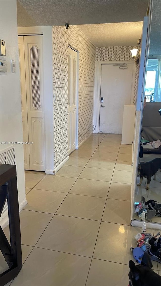 corridor with light tile patterned floors and a textured ceiling