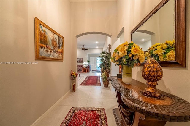 hallway with light tile patterned flooring and a towering ceiling