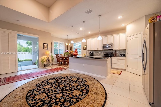 kitchen with pendant lighting, a center island with sink, tasteful backsplash, white cabinetry, and stainless steel appliances