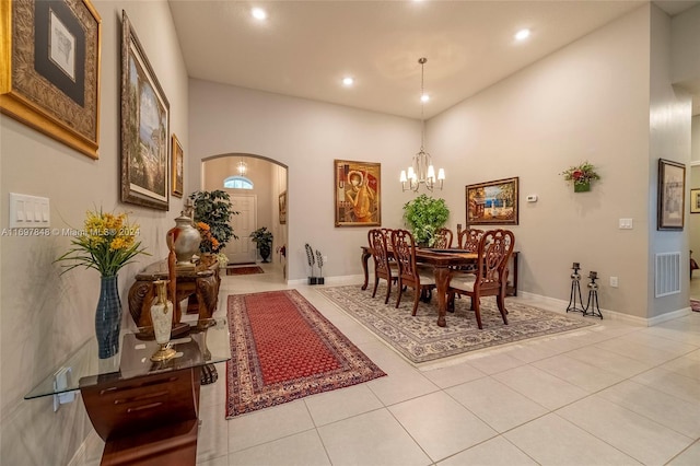 tiled dining area featuring a high ceiling and an inviting chandelier