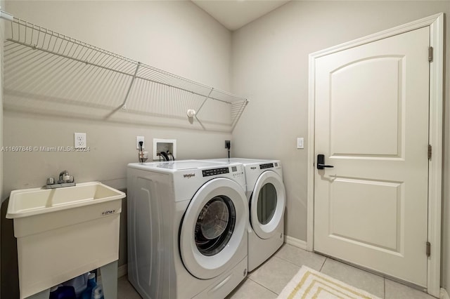 laundry area featuring washer and clothes dryer, light tile patterned flooring, and sink