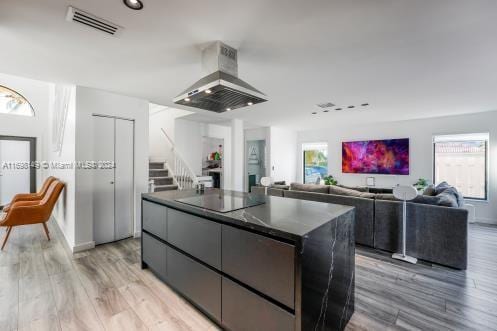 kitchen with black electric cooktop, light hardwood / wood-style flooring, a center island, and wall chimney range hood