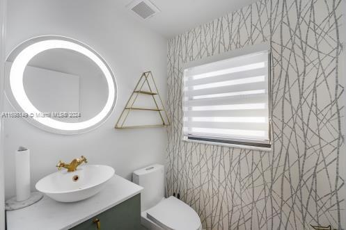 bathroom featuring vanity, tile walls, and toilet