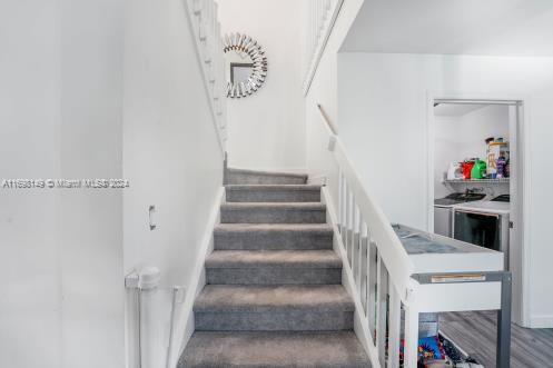 stairs featuring hardwood / wood-style flooring and separate washer and dryer