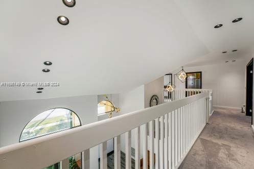 corridor featuring light colored carpet and lofted ceiling