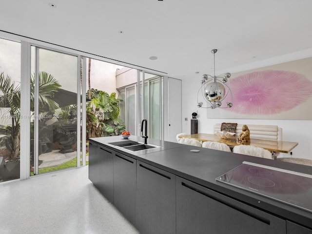 kitchen featuring stovetop, sink, a wall of windows, and decorative light fixtures