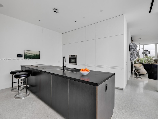 kitchen featuring white cabinetry, sink, oven, and a center island with sink