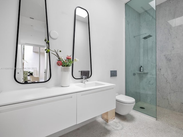 bathroom featuring a tile shower, vanity, and toilet