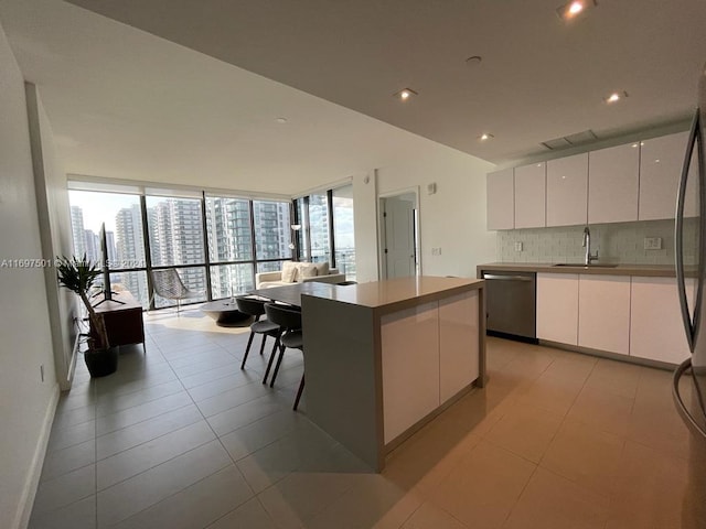 kitchen with dishwasher, a center island, white cabinets, sink, and plenty of natural light