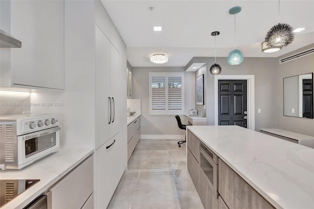 kitchen featuring white cabinets, light stone countertops, hanging light fixtures, and wall chimney range hood