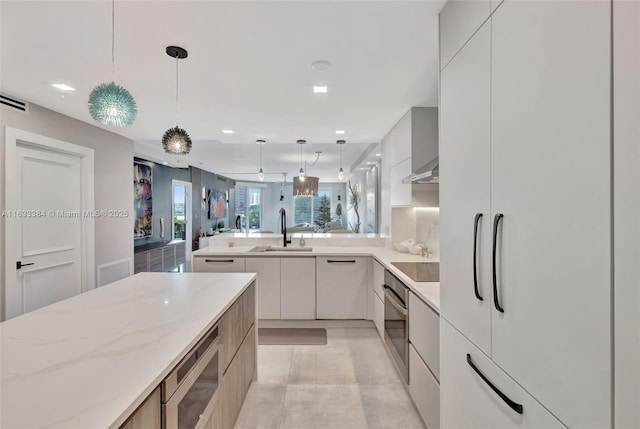 kitchen with pendant lighting, stainless steel appliances, light stone countertops, and sink