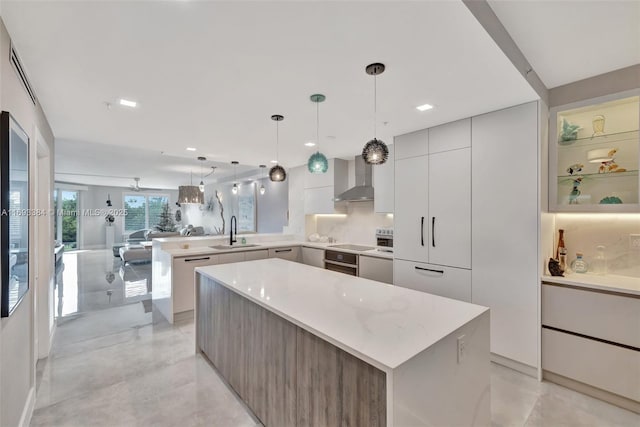 kitchen featuring sink, hanging light fixtures, a center island, white cabinets, and wall chimney exhaust hood