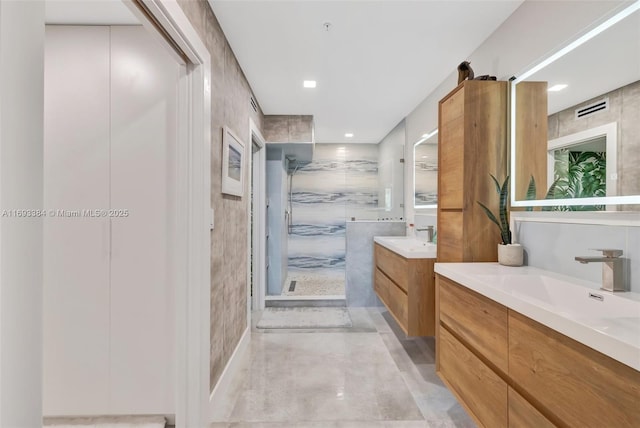 bathroom with vanity, a shower with door, and tile walls