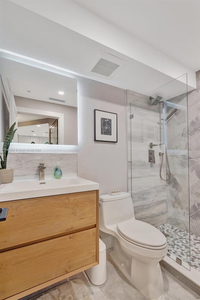 bathroom with vanity, a shower with door, and toilet