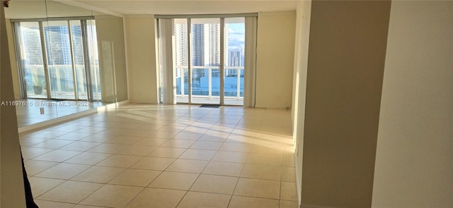 empty room featuring floor to ceiling windows, light tile patterned floors, and a wealth of natural light