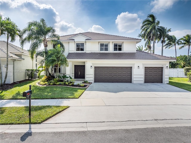 view of front of house with a garage, a front yard, and central AC