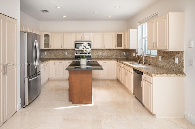 kitchen featuring stone counters, sink, backsplash, a kitchen island, and appliances with stainless steel finishes