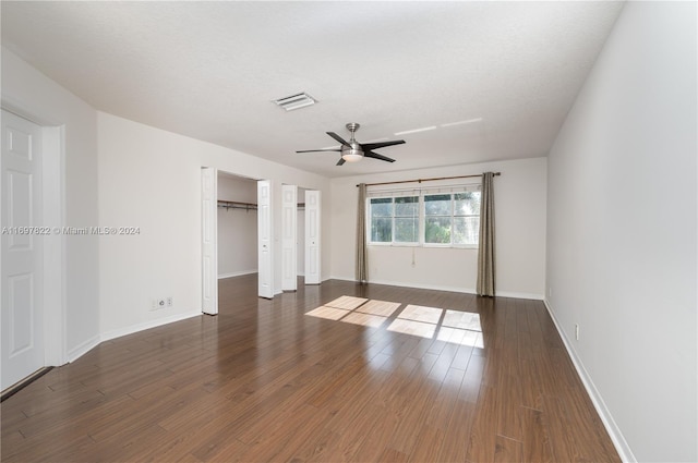 unfurnished room with a textured ceiling, ceiling fan, and dark wood-type flooring