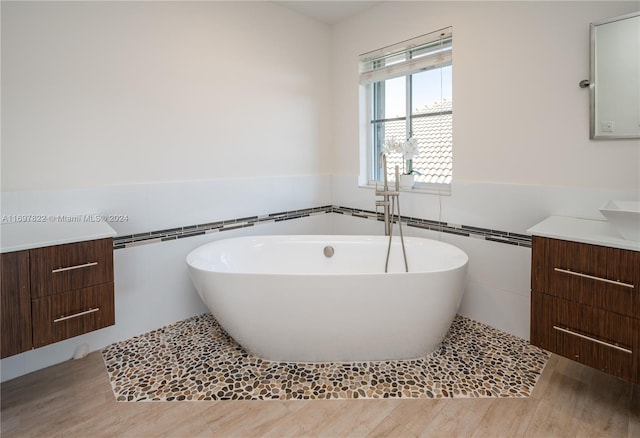 bathroom featuring vanity, hardwood / wood-style flooring, tile walls, and a bathing tub